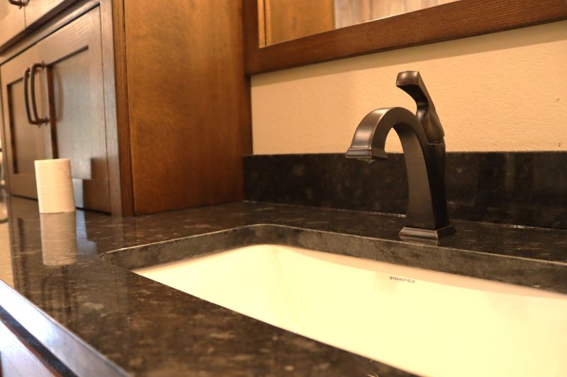 Bathroom sink faucet with granite countertop.